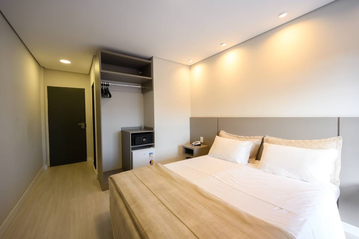 A hotel room with a bed, bedside table, and a built-in wardrobe.