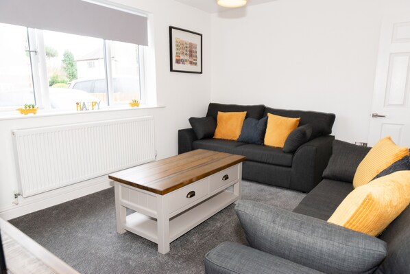A modern living room with a grey sofa, a wooden coffee table, and a radiator.