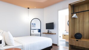 Ein modernes Hotelzimmer mit Bett, Nachttisch, Fernseher und einem Holzschrank.