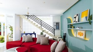 Ein modernes Wohnzimmer mit einem roten Sofa, einem Glastisch und einer Treppe, die in einen oberen Bereich führt.