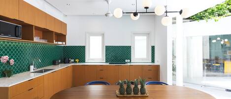 A modern kitchen with wooden cabinets, a green tiled backsplash, and a wooden dining table with chairs.