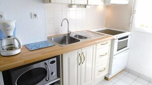 A kitchen with white cabinets, a stainless steel sink, a coffee maker, a microwave, and an oven.