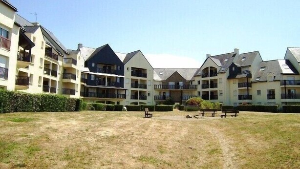 A courtyard with multiple-story buildings, outdoor seating, and a well-maintained lawn.