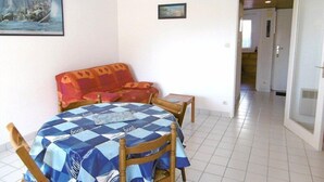 A dining area with a checkered tablecloth, a sofa, and a painting of a ship on the wall.