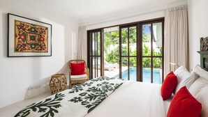 A bedroom with a large bed, a chair, a framed picture, and a view of a pool and garden. - Villa Atma (Seminyak)