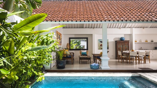 A poolside area with a tiled roof, a dining set, and potted plants. - Villa Atma (Seminyak)