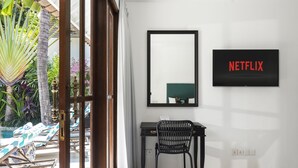 Une pièce comprenant un bureau, une chaise et un téléviseur affichant le logo de Netflix.