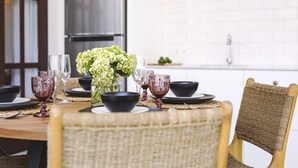 Una mesa de comedor puesta con cuencos negros, copas de vino y un florero con flores.