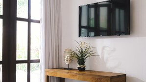 Un dormitorio con una cama, una mesita de noche de madera, una planta en maceta, un cráneo decorativo y un televisor montado.