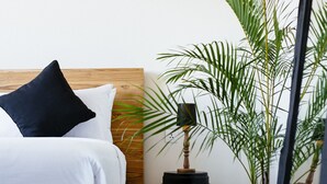 A neatly made bed with white and dark pillows, a wooden headboard, and a checkered floor. - Villa Soleh (Seminyak)
