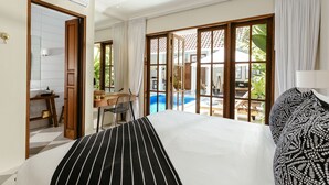 Una habitación de hotel con una cama grande, un escritorio y vistas a una piscina al aire libre.