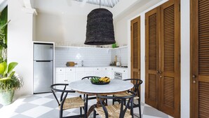 A kitchen with a round table, chairs, a hanging light fixture, and wooden cabinets. - Villa Alliv (Seminyak)