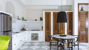 A modern kitchen with white cabinets, a stainless steel refrigerator, a gas stove, and a checkered floor. - Villa Alliv (Seminyak)