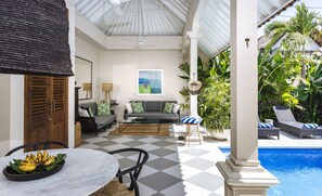 Un patio cubierto con suelo a cuadros, una piscina y exuberante vegetación tropical.