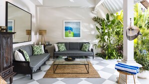 A living room with a checkered floor, a sofa set, a coffee table, a large mirror, and a wall-mounted artwork. - Villa Alliv (Seminyak)