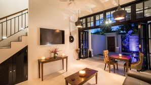 A spacious living area with a staircase, a flat-screen TV, a dining table with chairs, and a ceiling fan. - Pulau Rumah (Seminyak)
