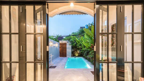 A pool area with a clear view through a glass door, a wooden door, and a tiled floor. - Villa Neno (Seminyak)