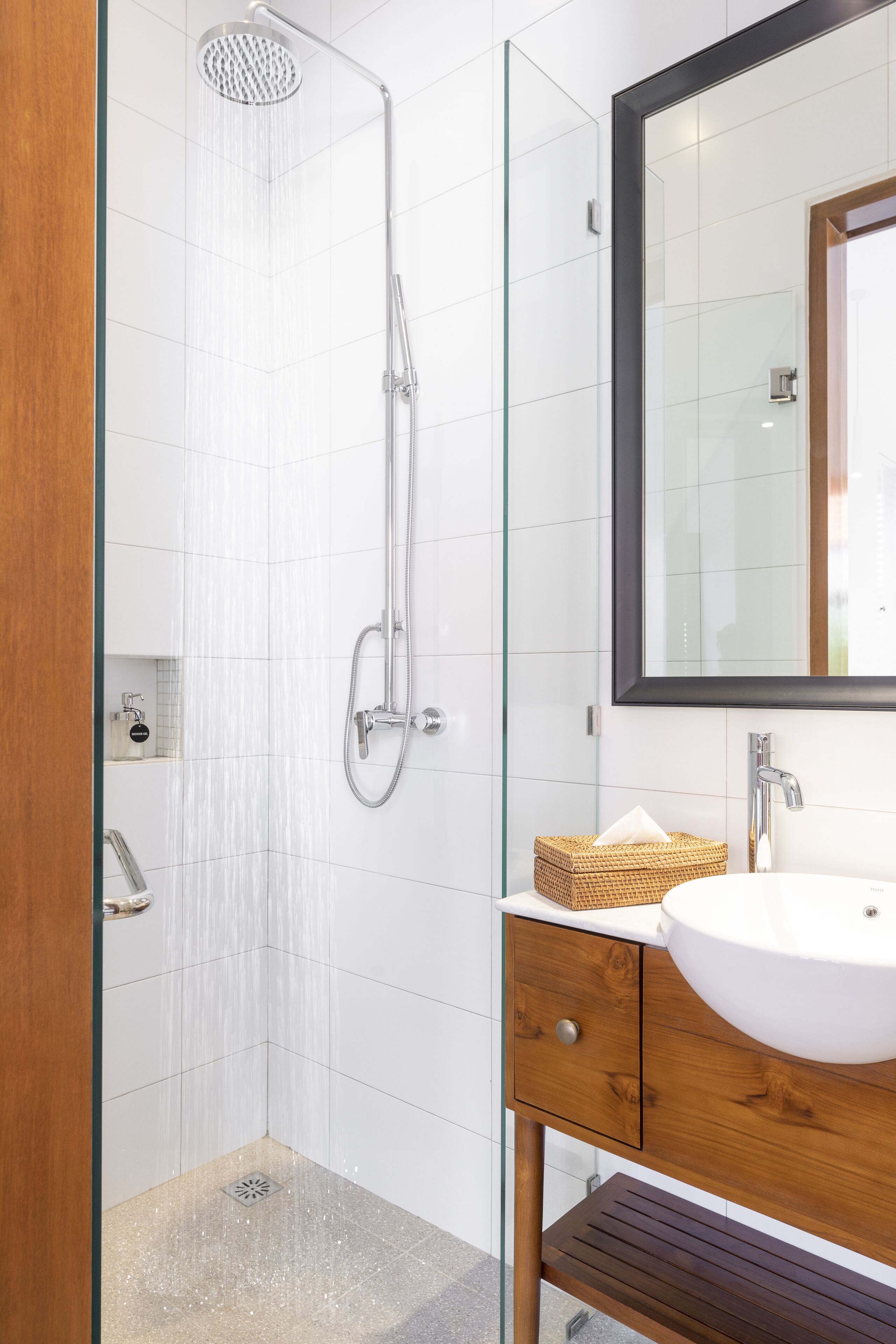 Une salle de bain moderne avec une douche à parois de verre, un meuble-lavabo en bois et un grand miroir.
