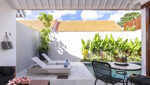 Un patio moderno al aire libre con piscina, sillas de descanso y plantas en macetas.