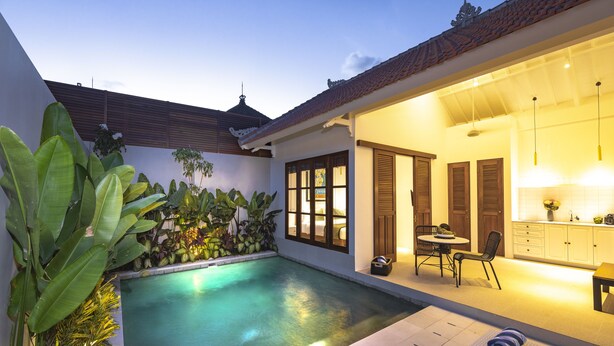 Un área de piscina privada con un comedor y una cocina visible a través de una puerta abierta.