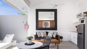 A modern kitchen with a dining area, a ceiling fan, and a large window. - Villa Pandi (Seminyak)