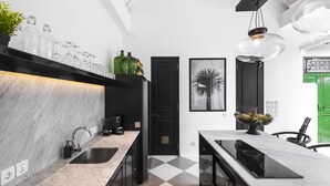 A modern kitchen with a black and white color scheme, featuring a marble countertop, black cabinets, a black door, and a black stove. - Villa Nago (Seminyak)