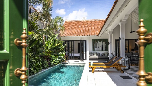 A pool area with a tiled roof, a lounge chair, and a small table. - Villa Nago (Seminyak)