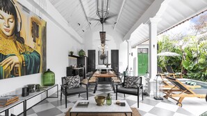 A spacious indoor area with a checkered floor, a dining table, chairs, a sofa, and a large painting on the wall. - Villa Nago (Seminyak)