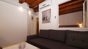 A cozy living room with a dark brown sofa, a wooden table with a clear cube, and a framed painting on the wall. - Apartments Stelina (Korcula)