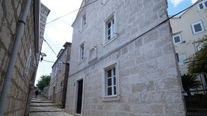 A narrow stone-paved street flanked by historic buildings with stone facades and traditional windows. - Apartments Galerija (Korcula)