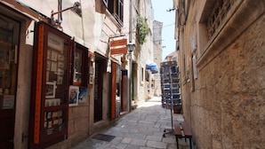 Une rue étroite bordée de boutiques des deux côtés, notamment une boutique d’art et une boutique de cadres.