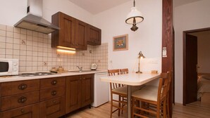 Une cuisine compacte avec des meubles en bois, un four à micro-ondes, un évier et une table à manger avec des chaises.