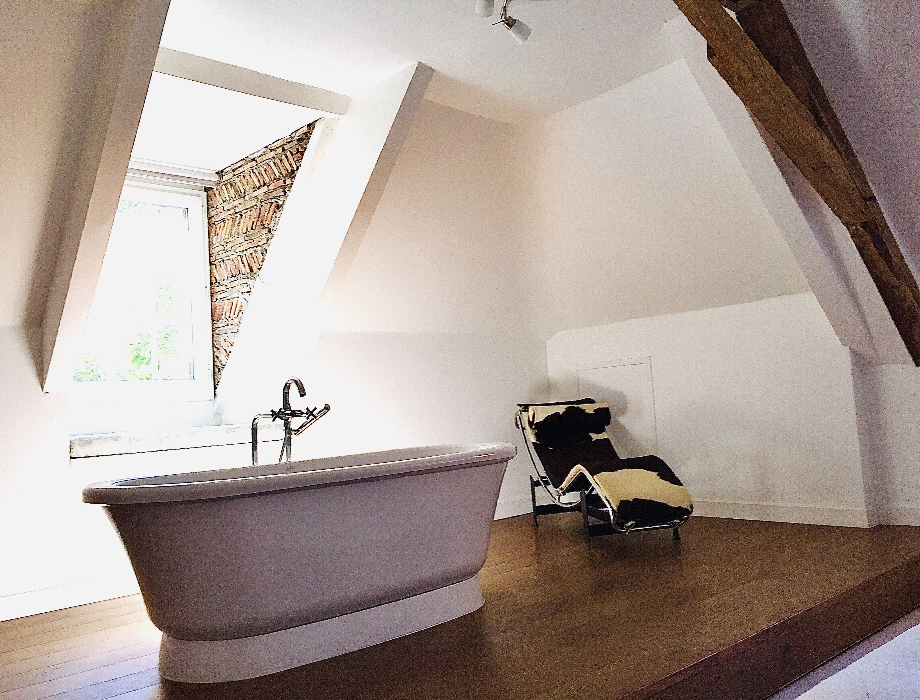 A bathroom with a freestanding bathtub, a towel rack, and a window with a view of greenery.