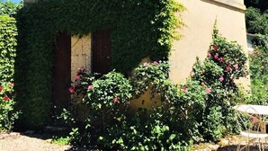 Um pequeno edifício com um relógio, rodeado por vegetação e um jardim.