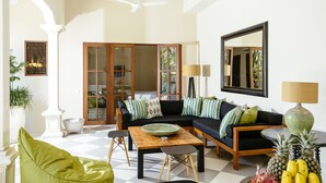 Una sala de estar moderna con sofá, mesa de centro y mesa de comedor. Hay un ventanal con vistas a zonas verdes.