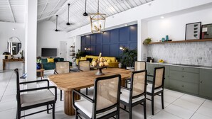 A modern kitchen with a wooden dining table, black chairs, and a blue accent wall. - Beachhouse (Canggu)