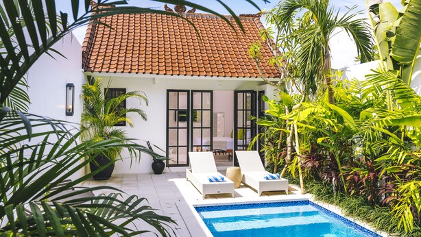 A house with a tiled roof, a swimming pool, and lounge chairs. - Town House (Canggu)