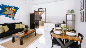 A modern living room with a black sofa, wooden coffee table, and a colorful abstract painting. - Town House (Canggu)