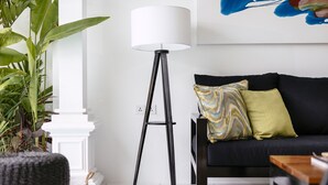 A modern living room with a black sofa, a floor lamp, and a potted plant. - Town House (Canggu)