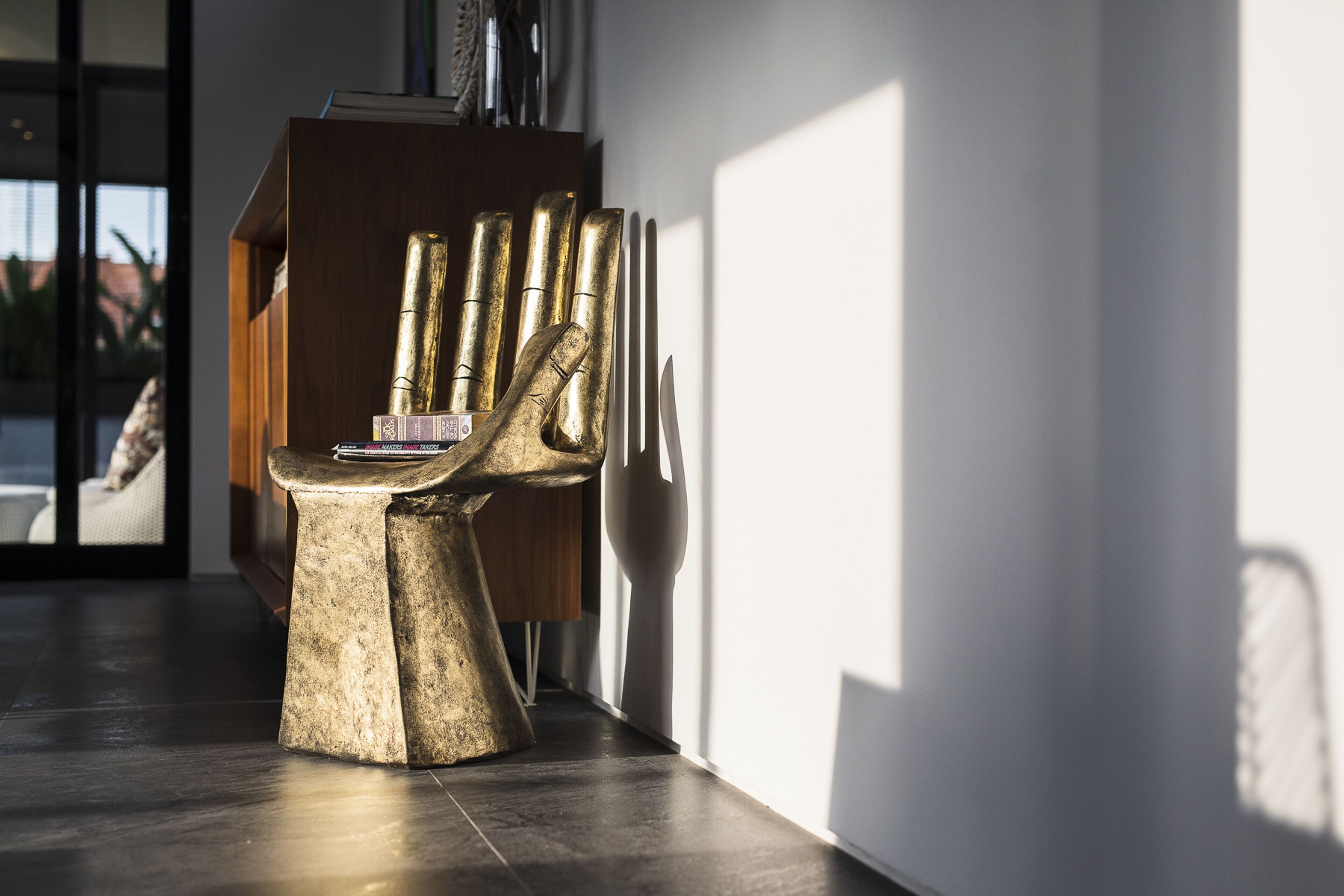 Un interior moderno con una silla dorada original y un mueble de madera.