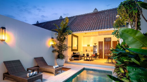 A poolside area with lounge chairs, a small table, and a potted plant. - Villa Salsa (Seminyak)