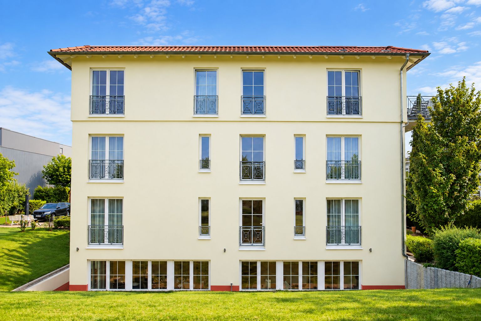 A multi-story building with a flat roof, large windows, and a balcony on each floor.