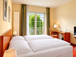 A hotel room with a double bed, a desk with a chair, a TV, and a window with curtains. - Hotel Zielonka (Hochheim am Main)