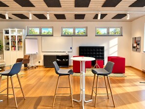 A modern meeting room with a whiteboard, a projector screen, a black sofa, and red seating. - Hotel Zielonka (Hochheim am Main)