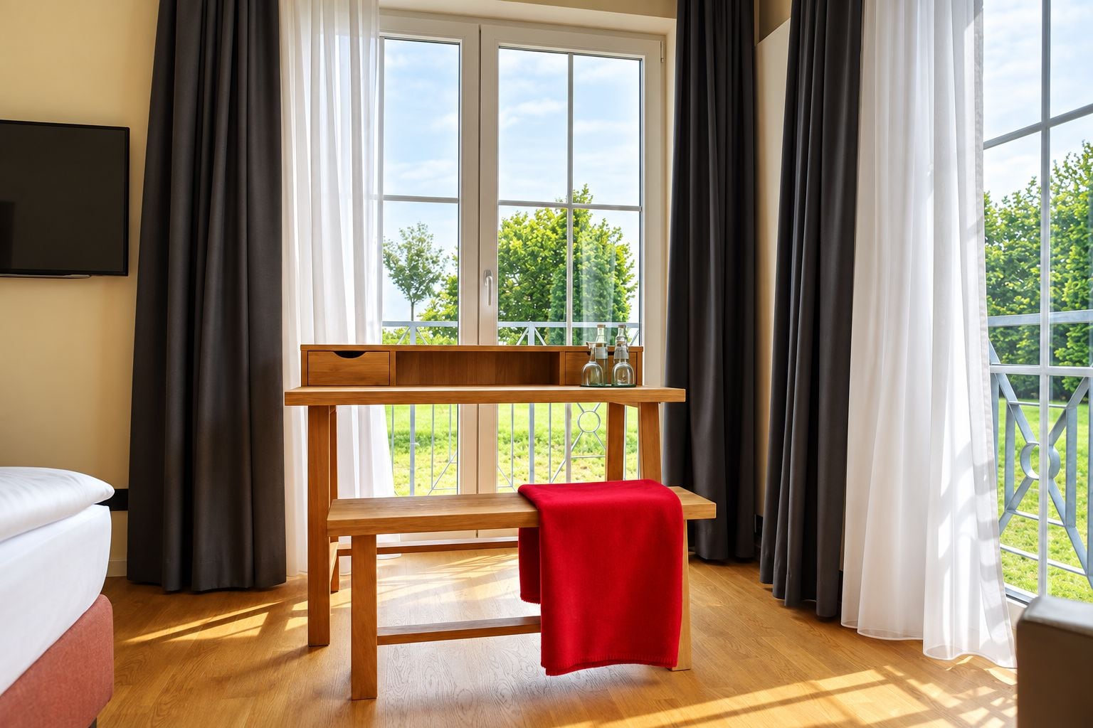 A room with a wooden bench, a small table with bottles, and a view of greenery outside.