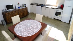 Un coin repas avec une table en bois, des chaises blanches et une nappe en dentelle.