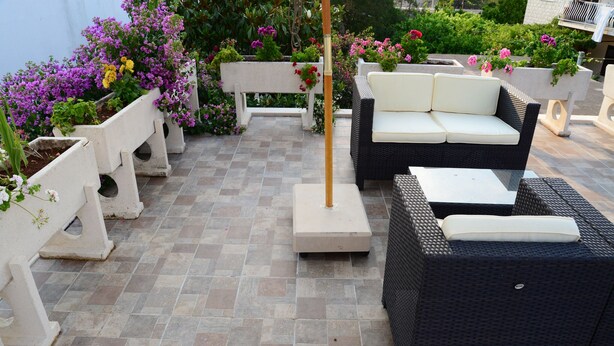 Un espace extérieur aménagé avec des meubles en osier et des jardinières fleuries.