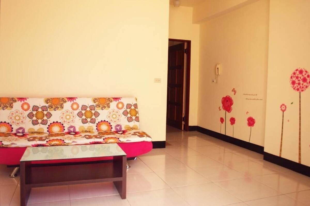 Un pasillo con un sofá, un banco, una puerta y una pared decorada con motivos florales.
