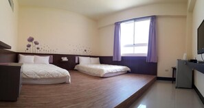 Una habitación de hotel con dos camas, un escritorio, un televisor y una ventana con cortinas.