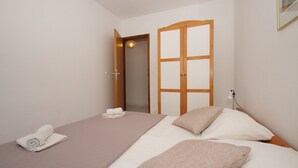 A bedroom with a bed, a bedside table, a towel, and a wardrobe. - South Island Apartments (Korcula)